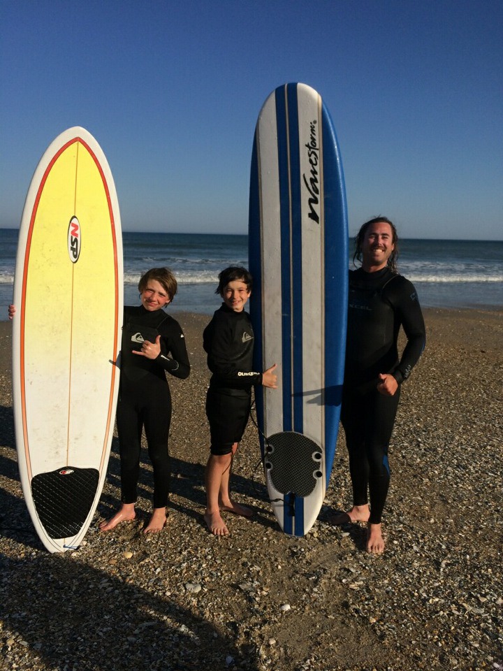 Guy and kids with surfboards