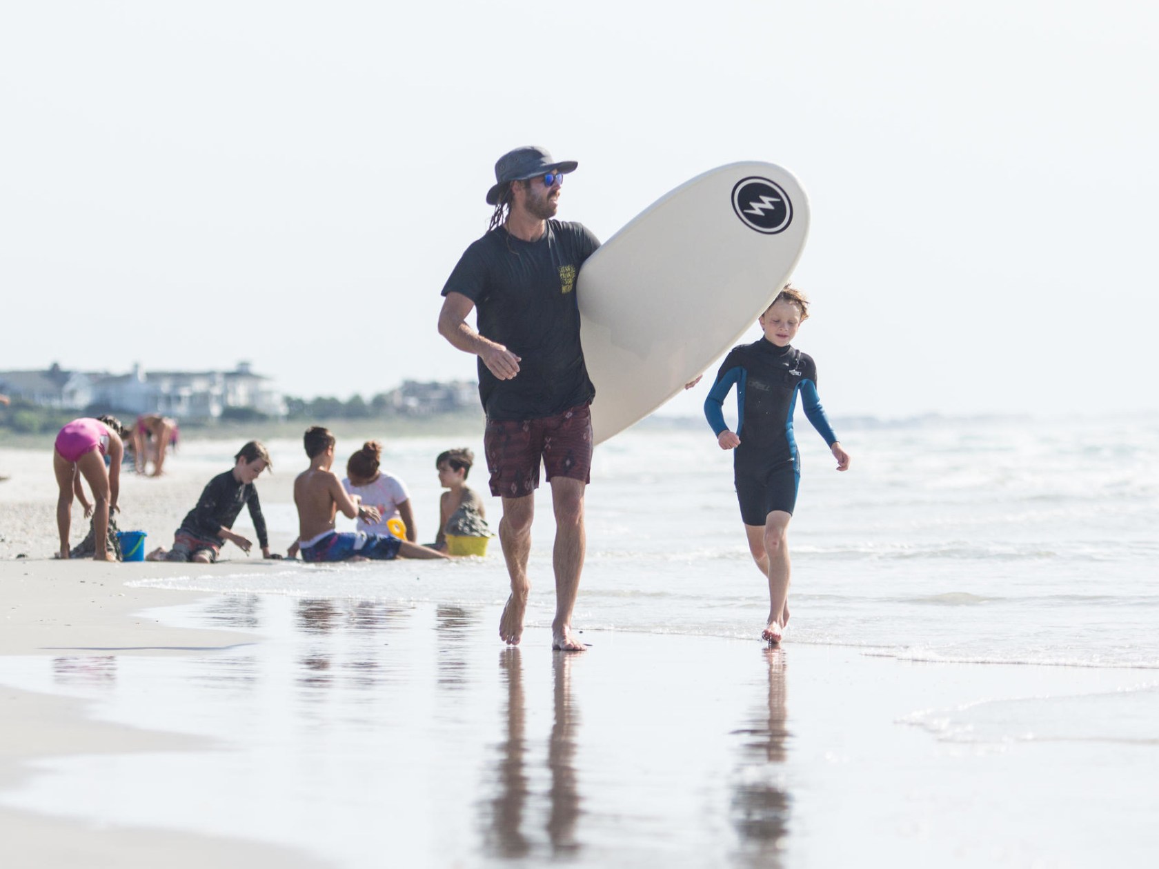 a man standing on top of a sandy beach holding a surf board